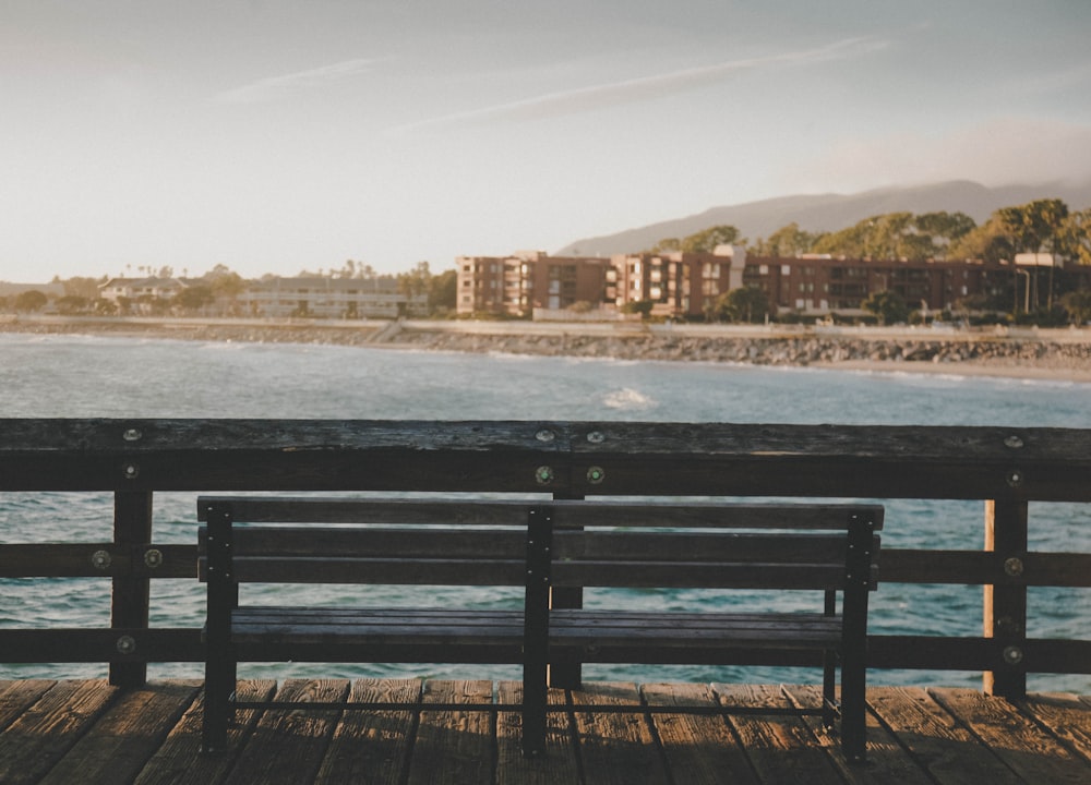 a bench sitting on top of a wooden pier next to the ocean