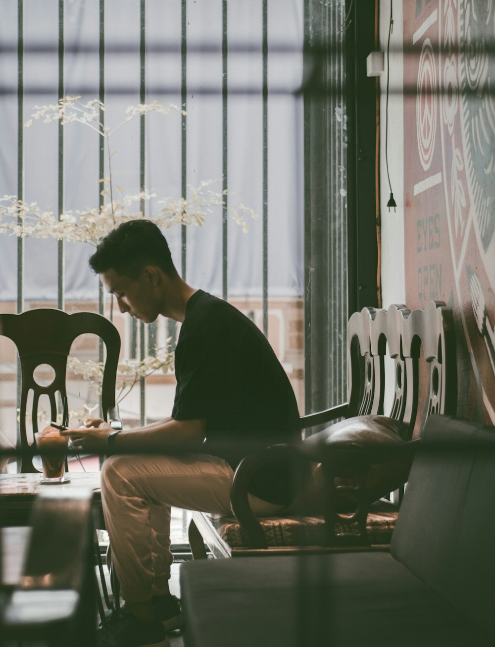 man wearing black shirt sitting on chair holding phone