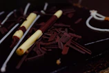 Close-up of a glossy chocolate entremet with delicate gold leaf accents.