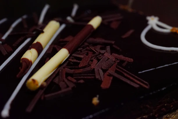 A close-up of a chef’s hands decorating a delicate chocolate dessert with precision.