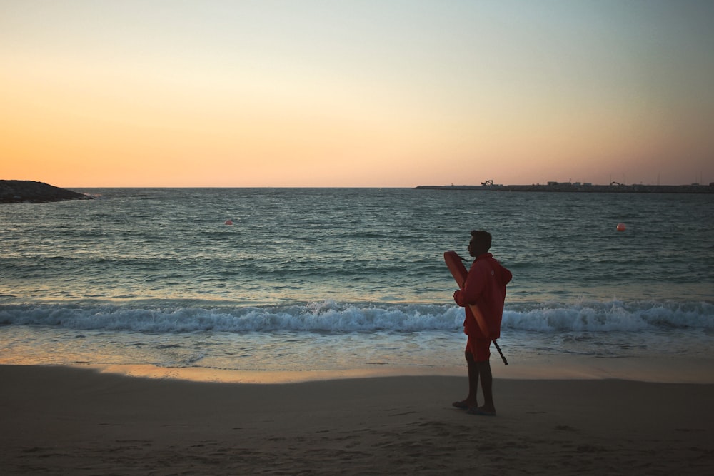 silhouette of person standing on seashore during golden hour