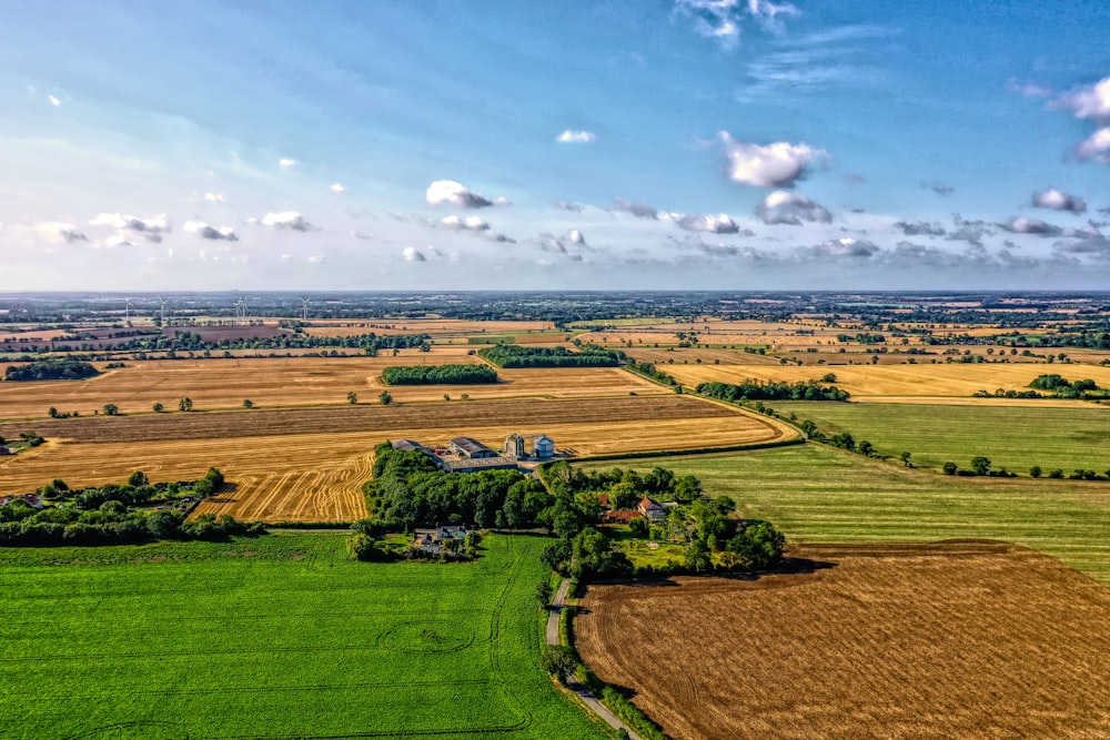 brown and green fields under cloudy sky during daytime