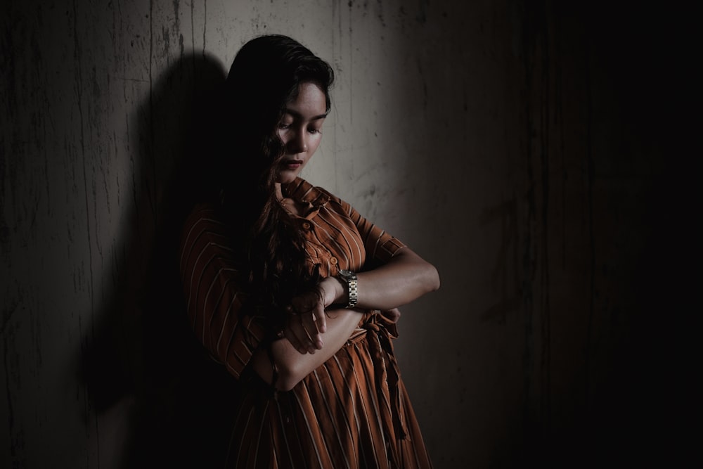 woman wearing orange dress standing and lean on wall