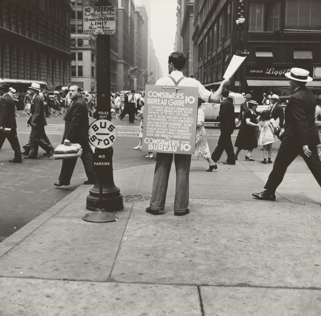 gray-scale photography of man with board on back with texts