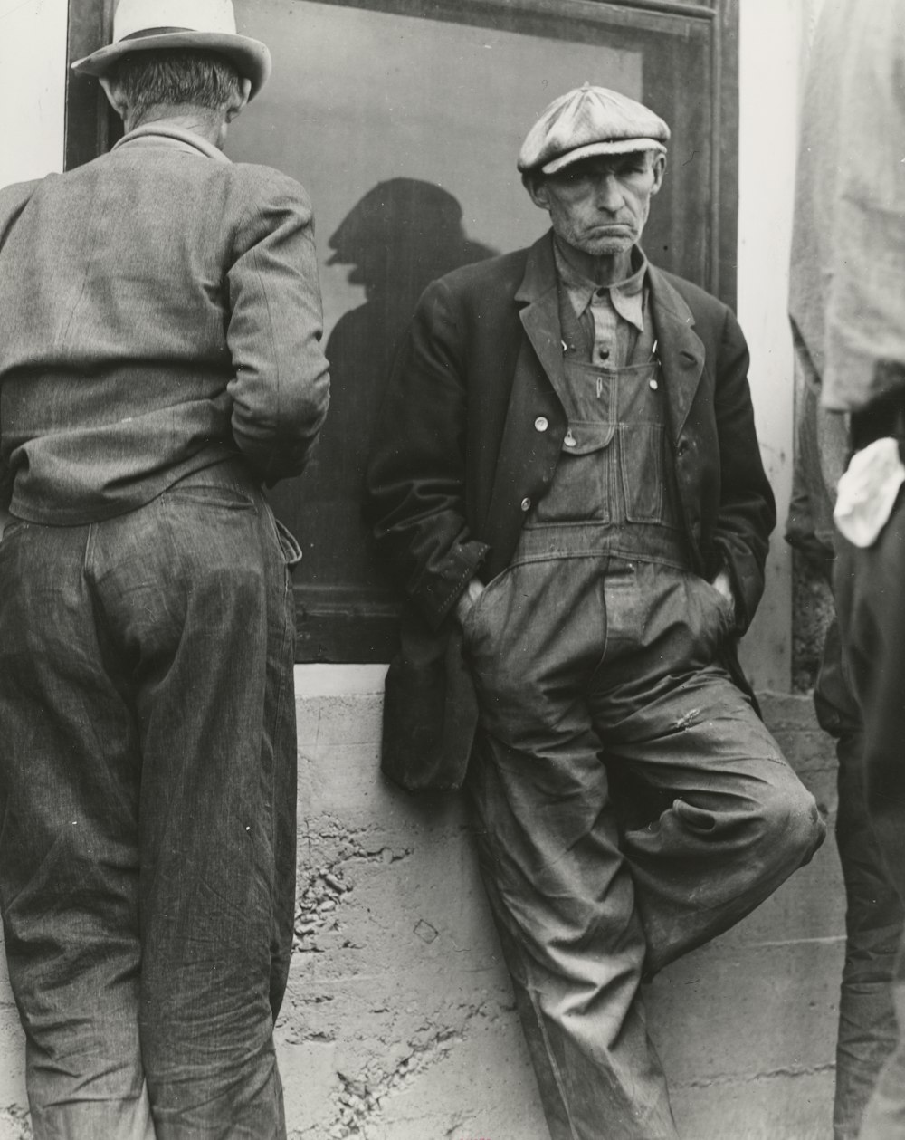 grayscale photography of two men standing near wall