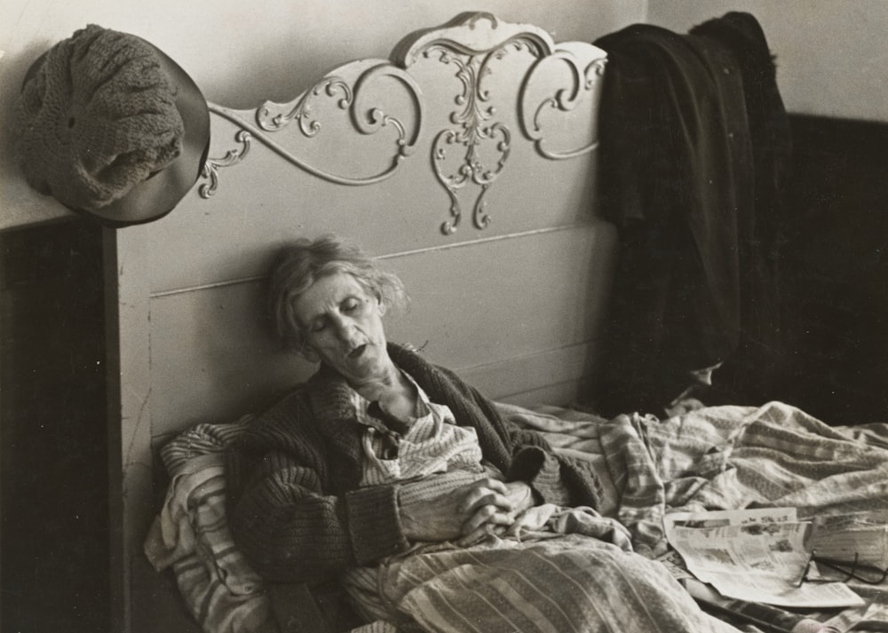 grayscale photography of woman lying on bed