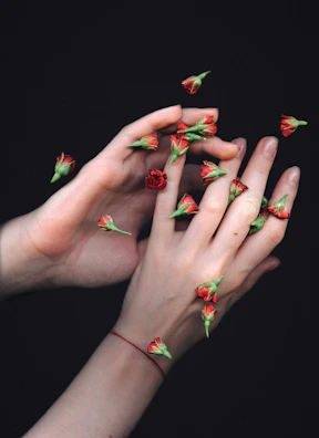 A close-up of delicate hands holding a single red rose, evoking sensuality.