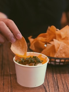 person holding chip pointing on sauce