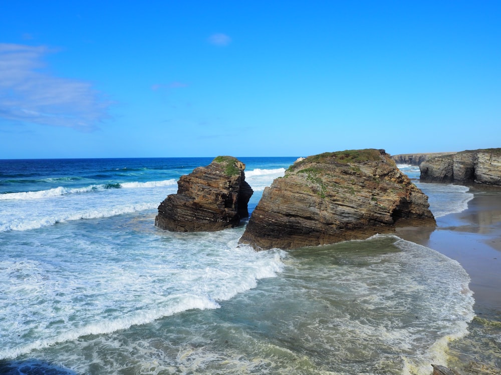 rocks near seashore viewing sea under blue and white skies