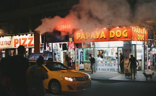 people walking near building beside vehicles during night time