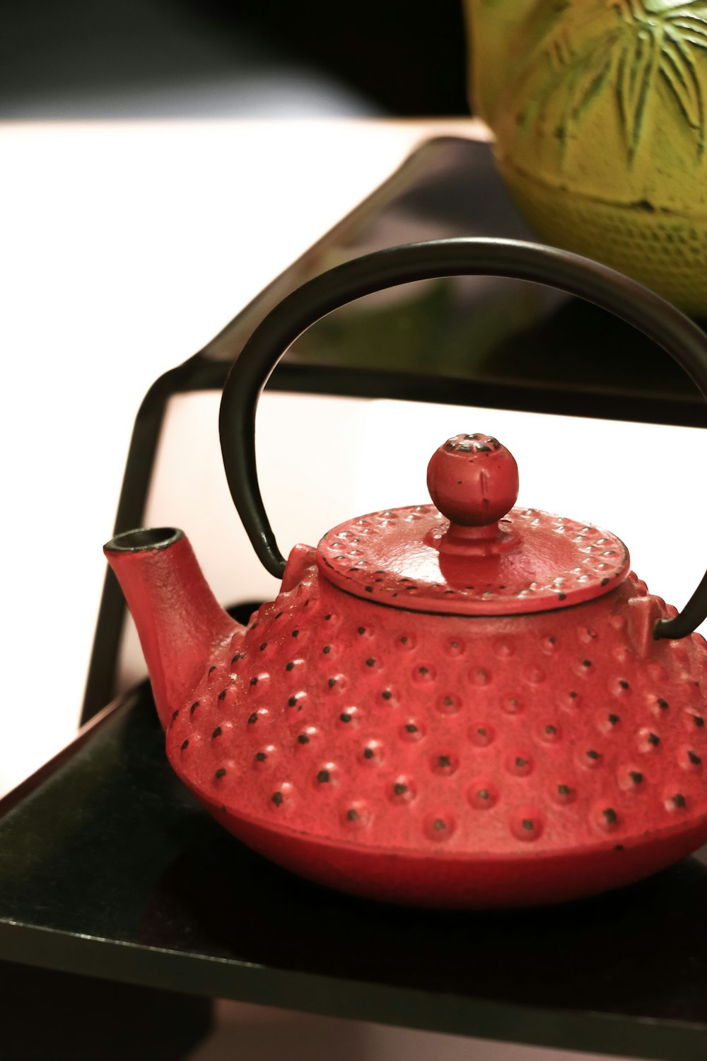 red and black ceramic teapot on black plank