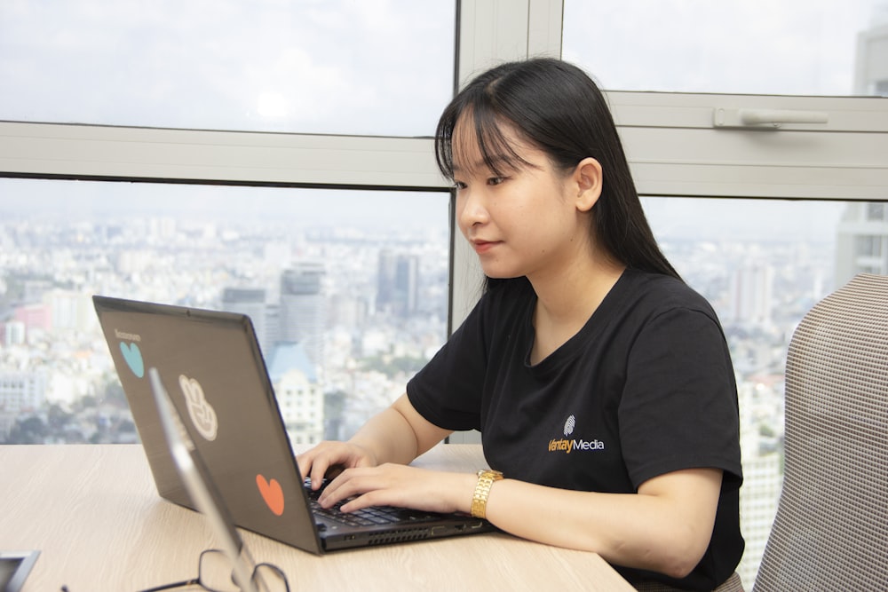 Mujer en camisa negra usando computadora portátil gris