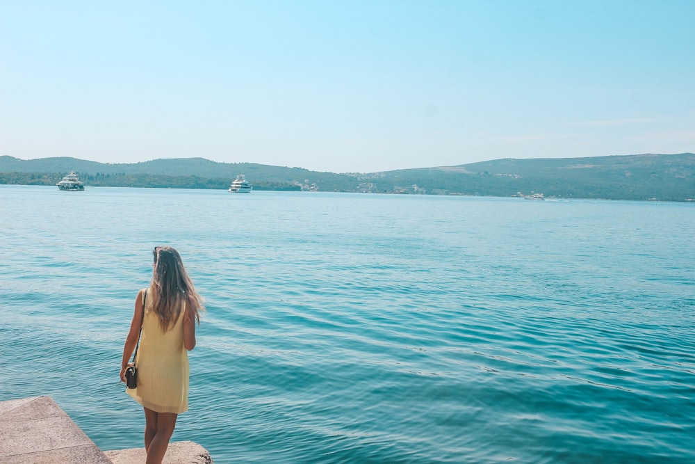 woman in white dress standing on rock by the sea