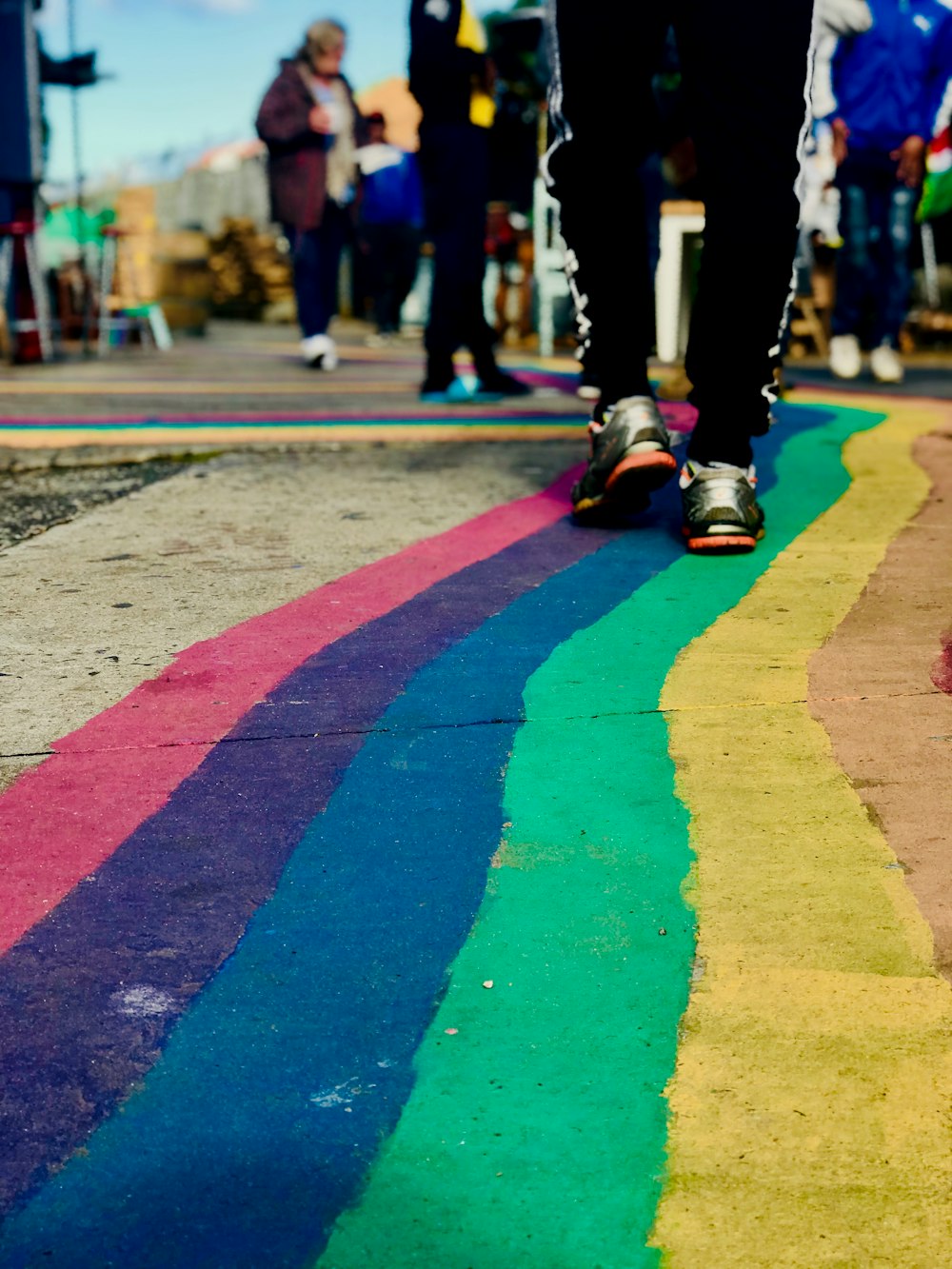 a person walking down a rainbow colored sidewalk