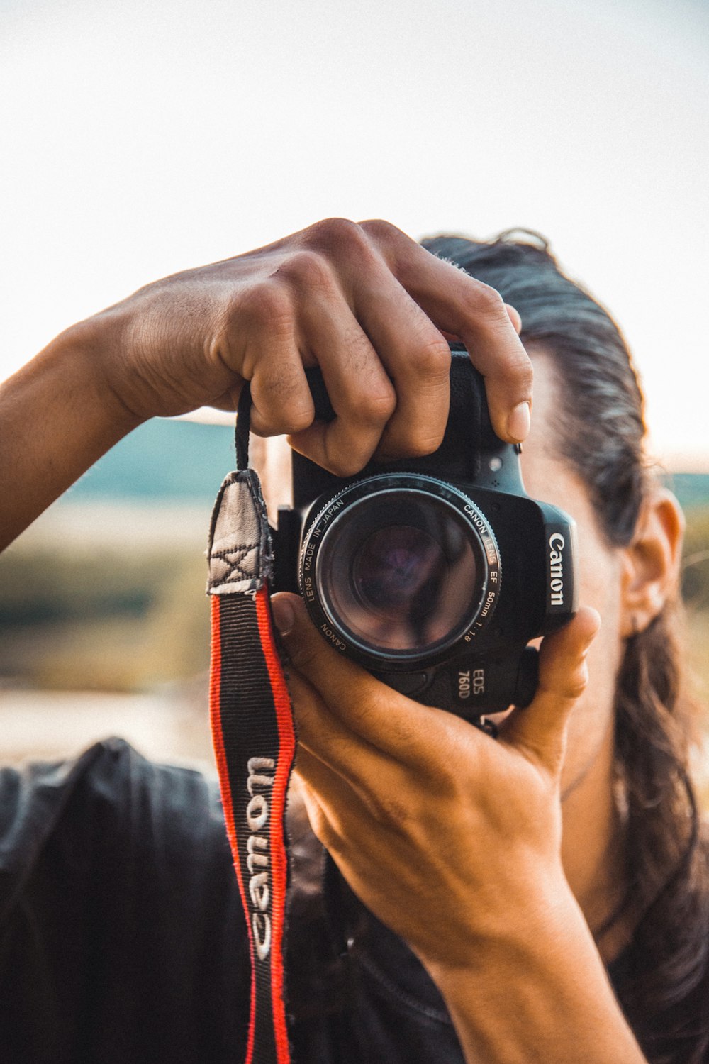 personne tenant un appareil photo Canon noir photographie en gros plan