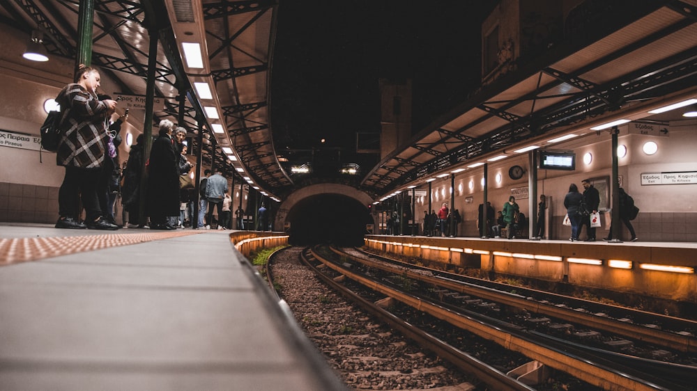 people standing beside train railway close-up photography