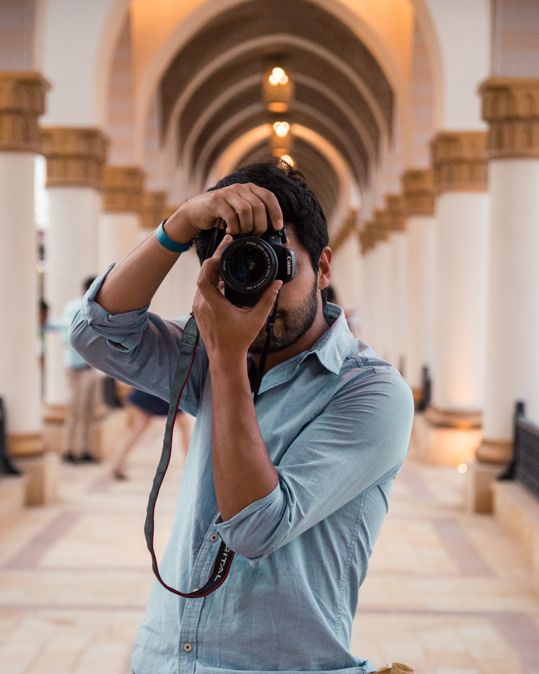 Indian photographer shooting with a DSLR in a pillared corridor