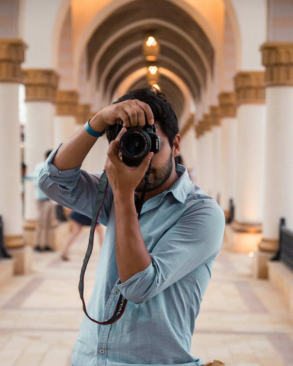 uomo che tiene la fotocamera DSLR