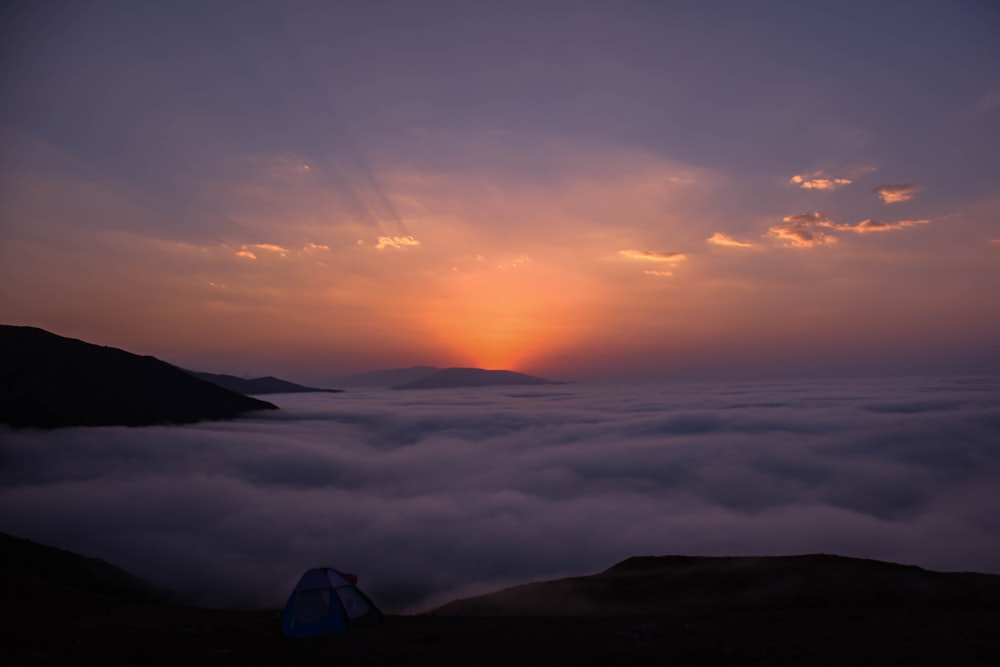 a tent sitting on top of a mountain under a cloudy sky