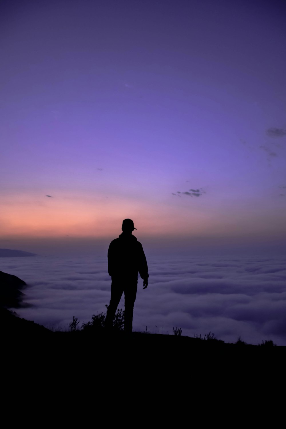 silhouette of person standing on cliff during golden hour