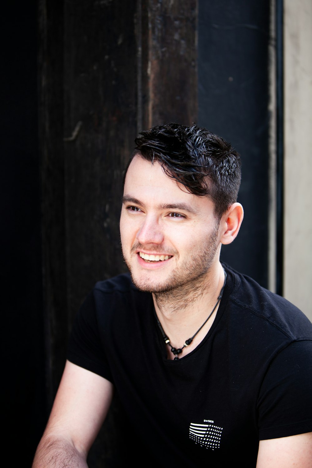 a man with a black shirt and a black necklace