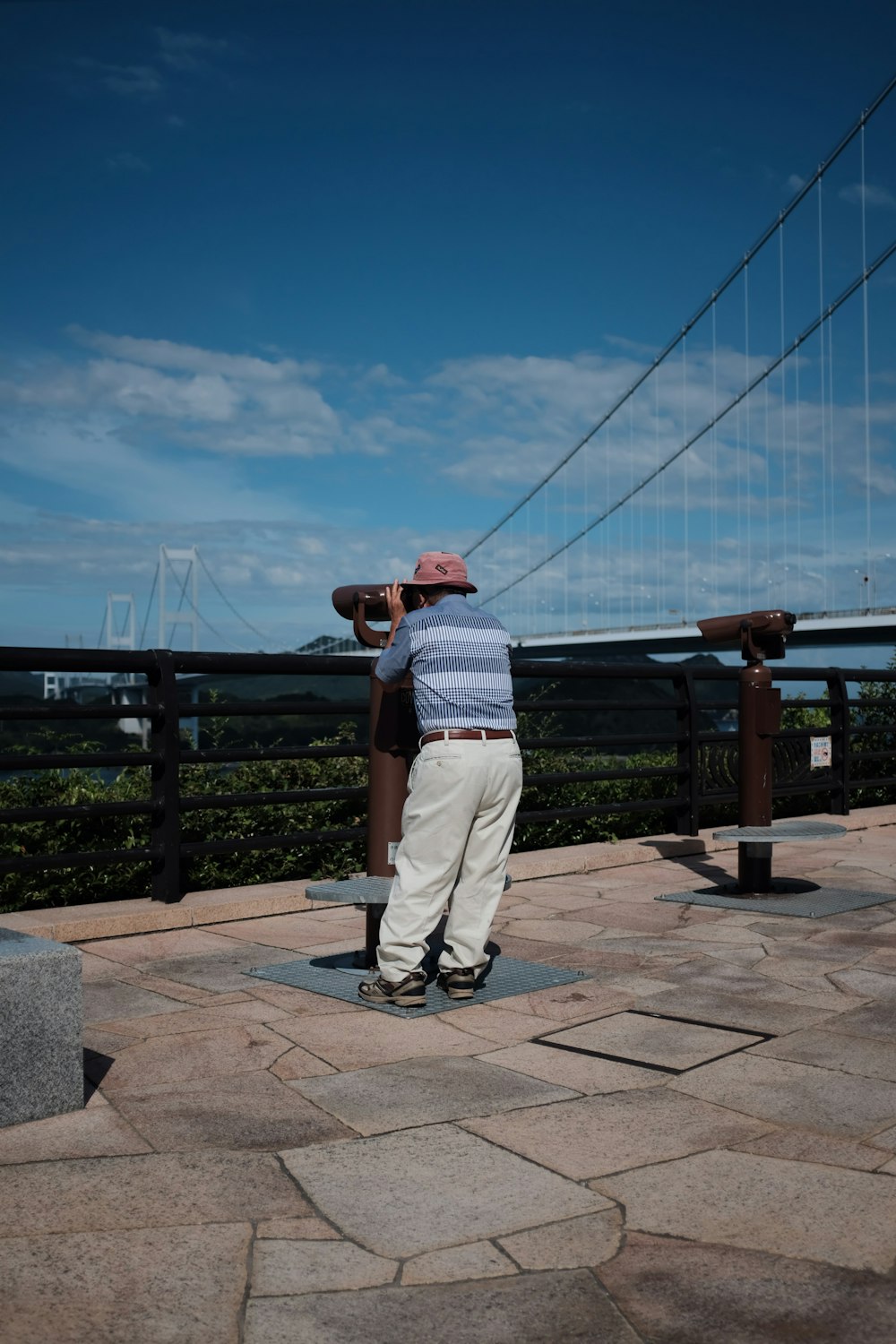 standing man wearing striped shirt using viewing telescope