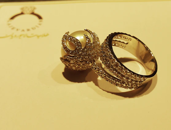 Close-up of an ornate rococo-style gold ring with intricate floral patterns and sparkling gemstones.
