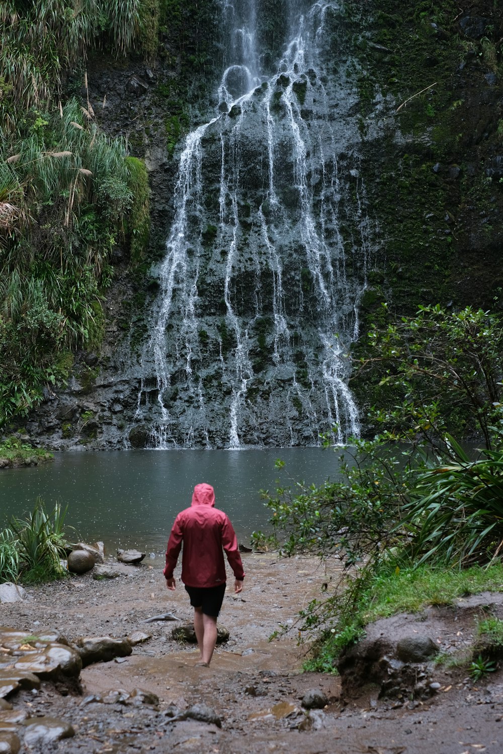 man walking towards a multi-tier waterfall