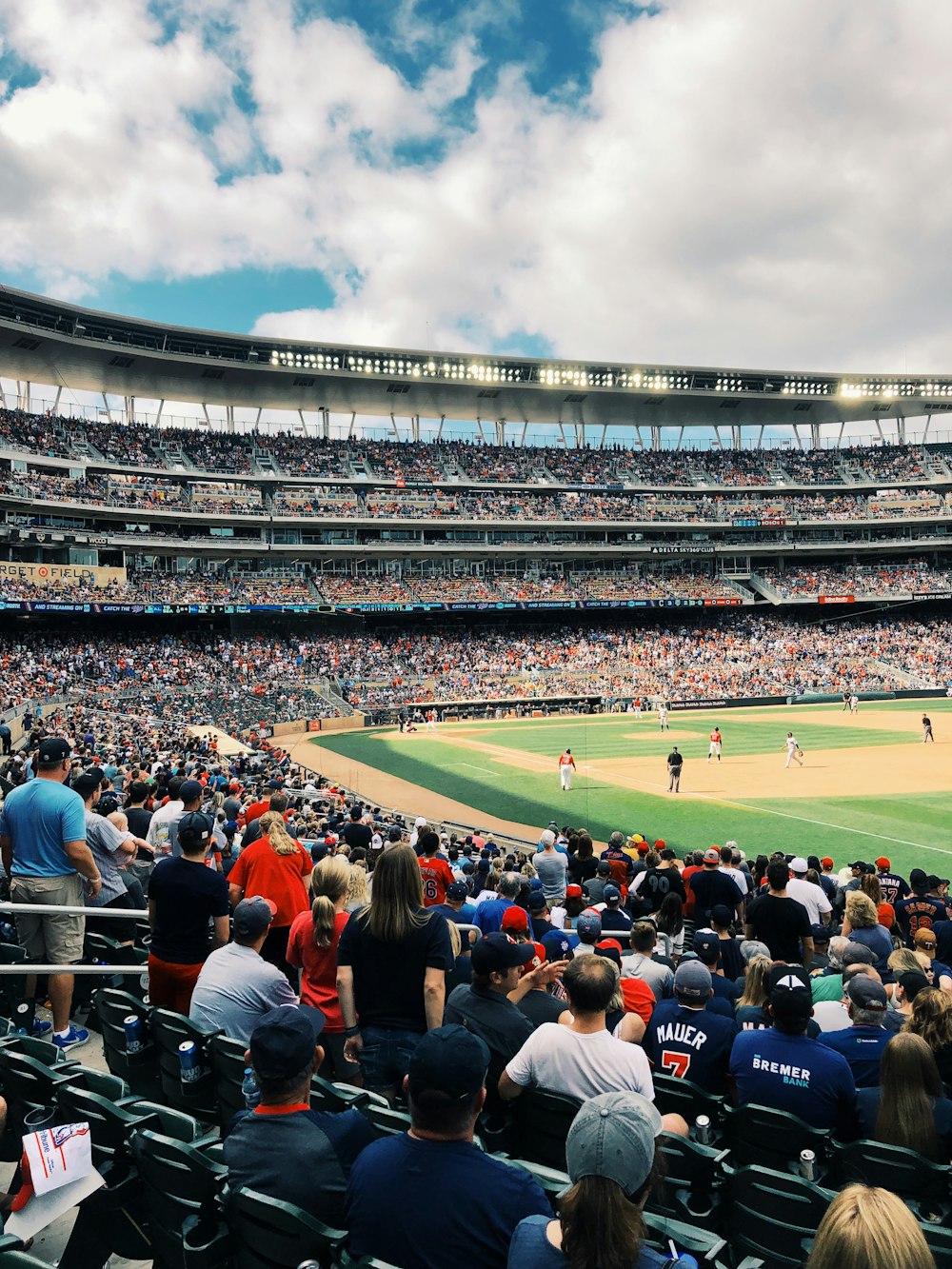 people watching baseball game under blue and white skies