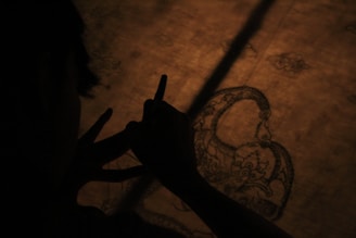 A skilled artisan hand-painting a gold leaf sign in a workshop filled with tools and materials.