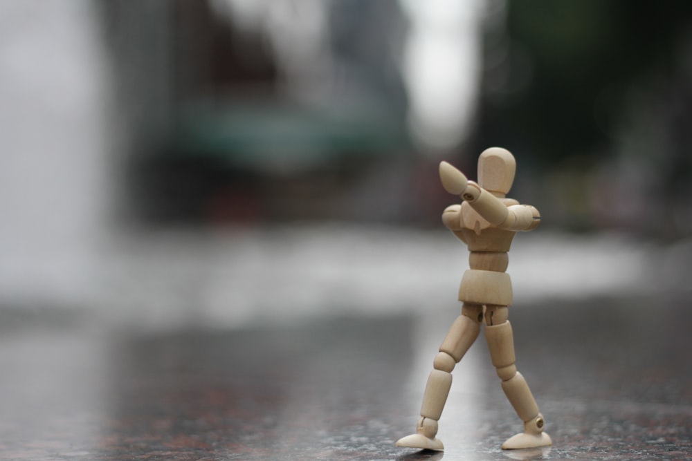 a small wooden toy standing on a wet surface