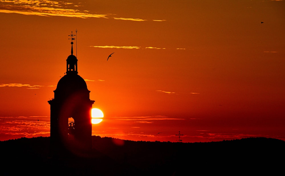 the sun is setting behind a clock tower