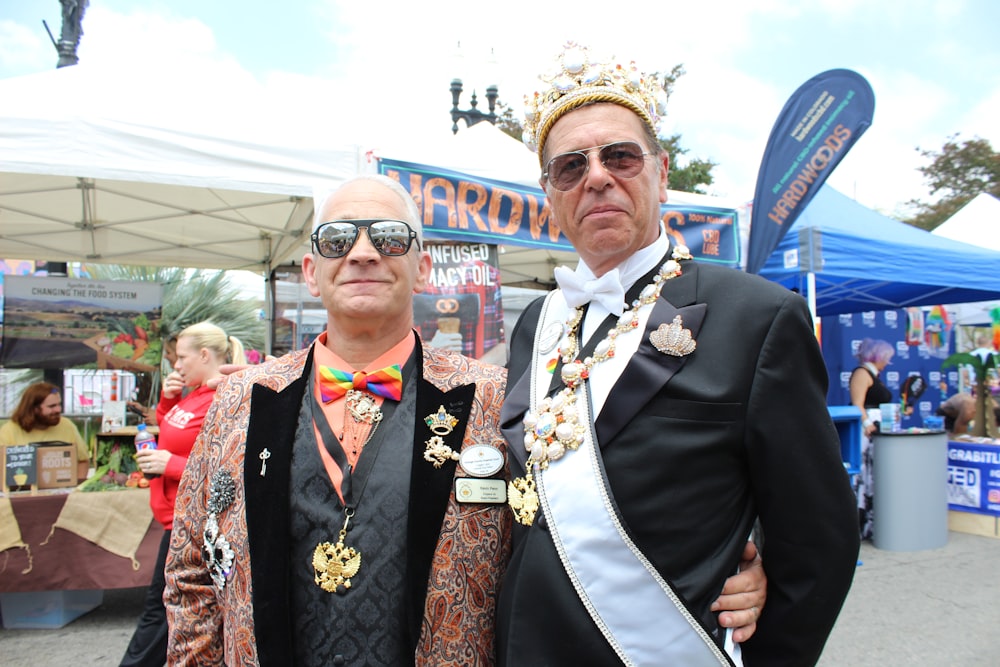 two men standing and smiling near people