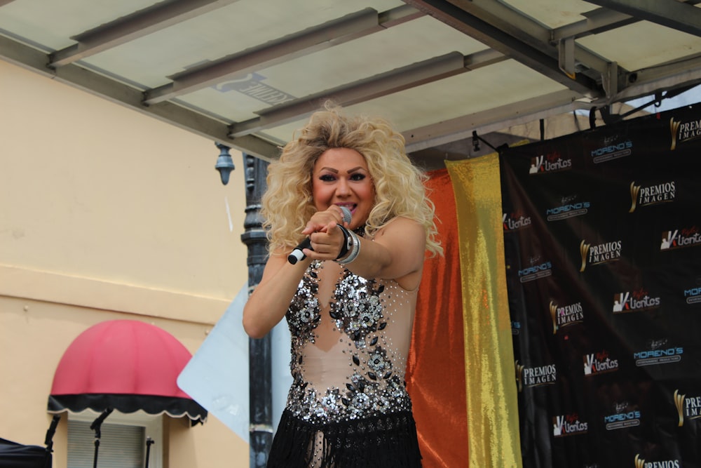 a woman in a silver and black dress holding a microphone