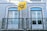 A building facade featuring intricate blue and white tile patterns typical of Portuguese architecture, with two windows framed by ornate wrought iron railings. A bright yellow flag with the text 'Back to Lisbon Hostel' adds a vibrant touch to the scene.