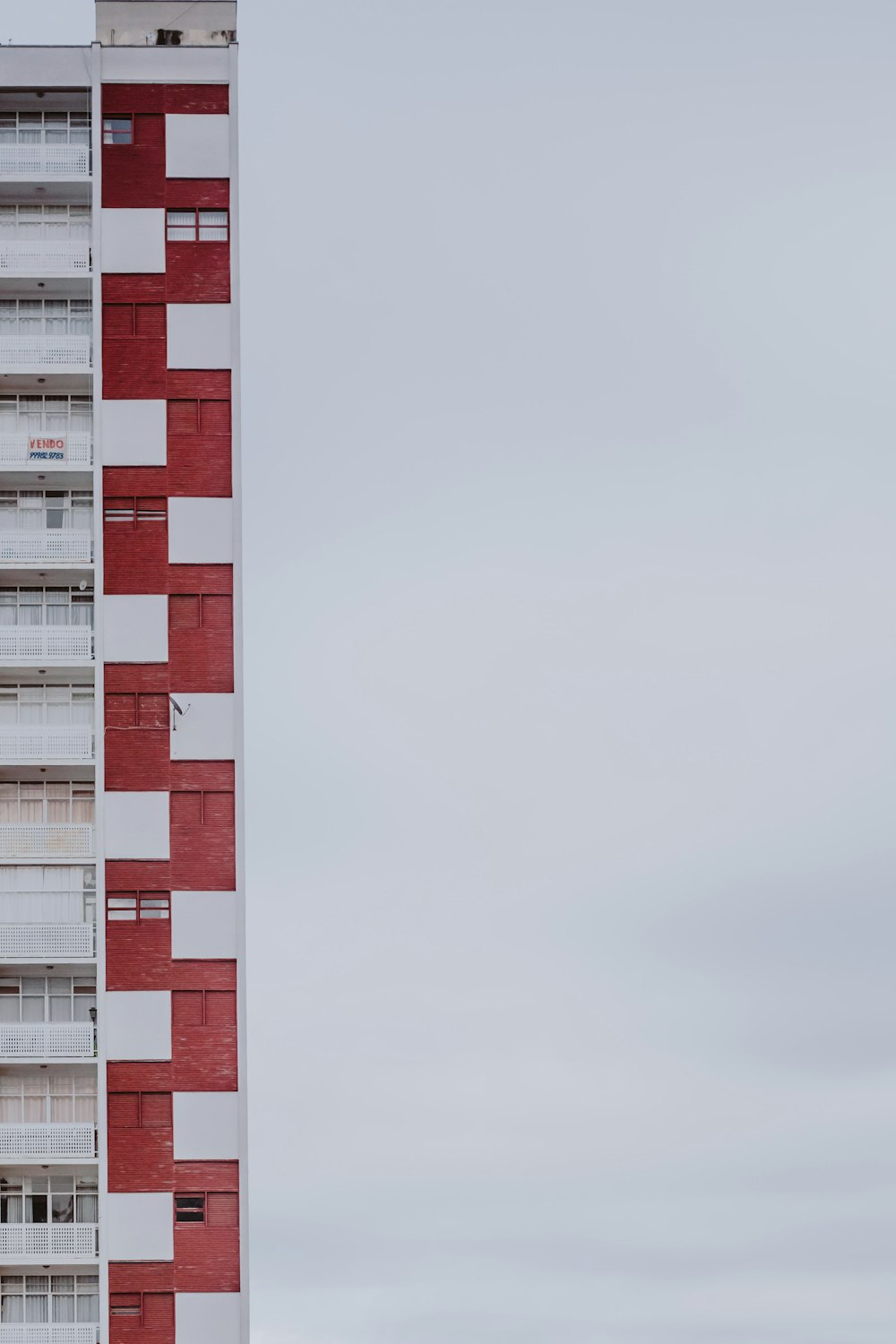 a tall red and white building with balconies