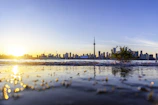 A scenic view of a Canadian city skyline at sunset with people walking nearby