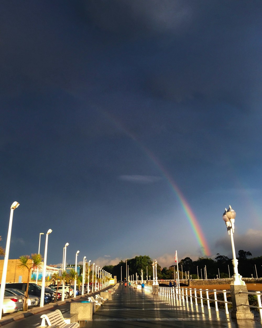 um arco-íris no céu sobre uma rua da cidade