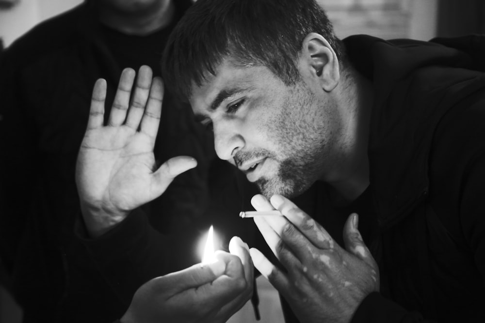 grayscale photo of man about to blow on flame