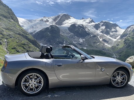 A sleek, modern car parked on a scenic road with mountains in the background.