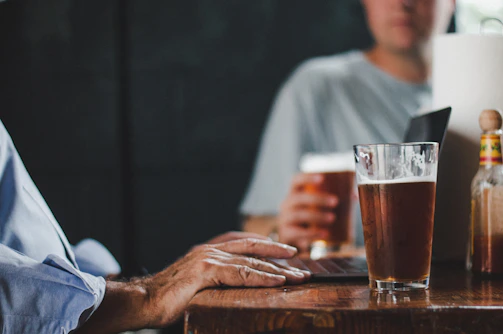 Close-up of members sharing homebrew samples around a rustic wooden table.