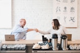 A smiling client shaking hands with a consultant in a modern meeting room.