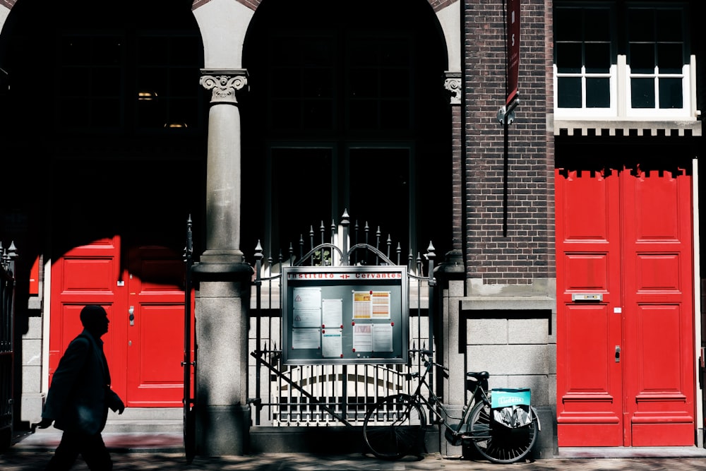 man walking near building with closed doors and gate