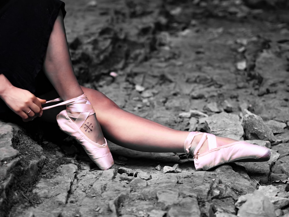 person sitting and fixing ballet shoes