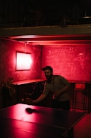 A group of players intensely focused during a fast-paced table tennis rally under purple lighting.
