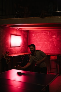 A group of diverse people playing table tennis in a community center.