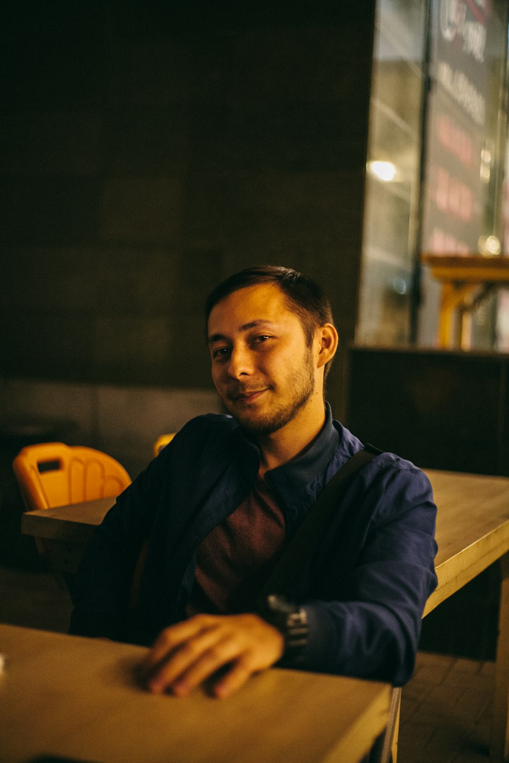 man sitting and smiling beside tables