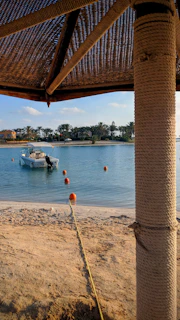 A cozy boat docked by a sandy beach with palm trees swaying.