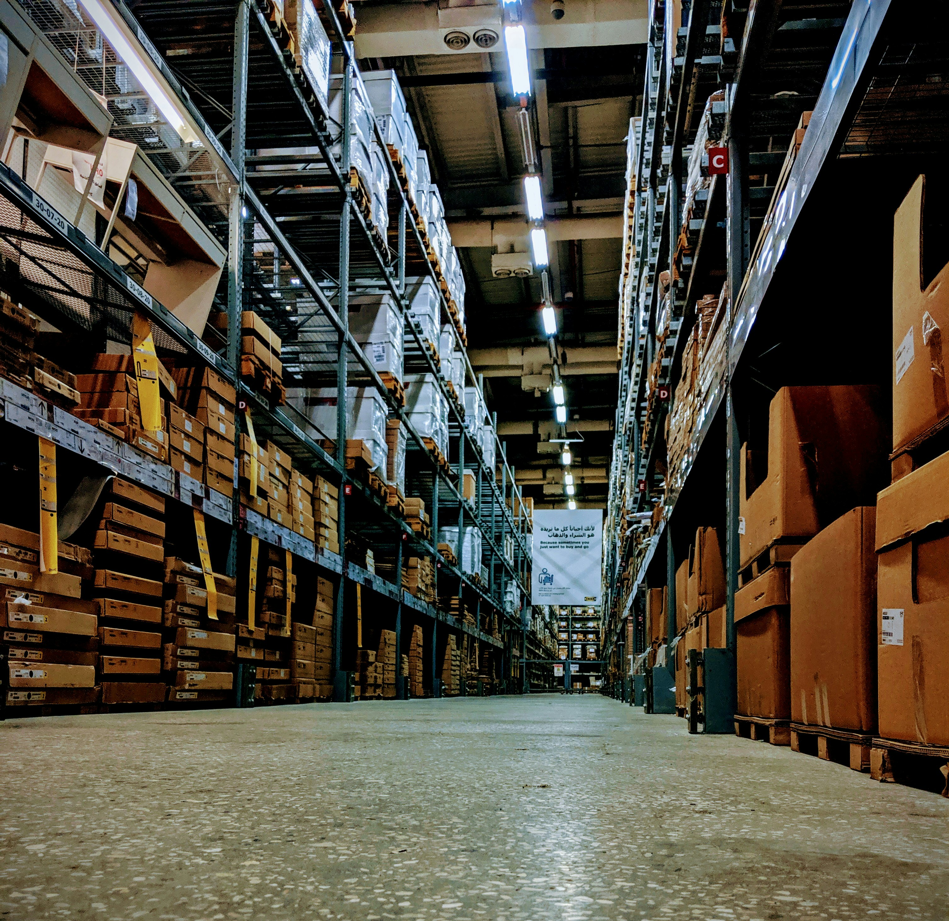 Organized warehouse with stacked tile boxes and bright overhead lighting in spacious logistics center