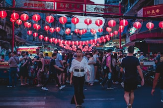 A vibrant street scene in Guangzhou at dusk, with glowing red lanterns and bustling market stalls.